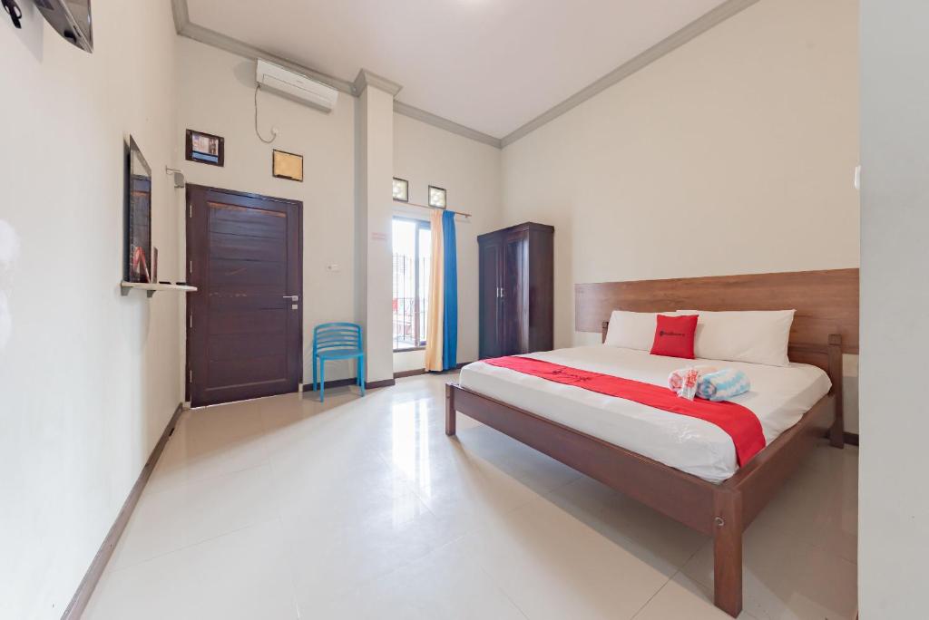 a bedroom with a bed with a red and white sheets at RedDoorz near GOR Sempaja Samarinda in Samarinda