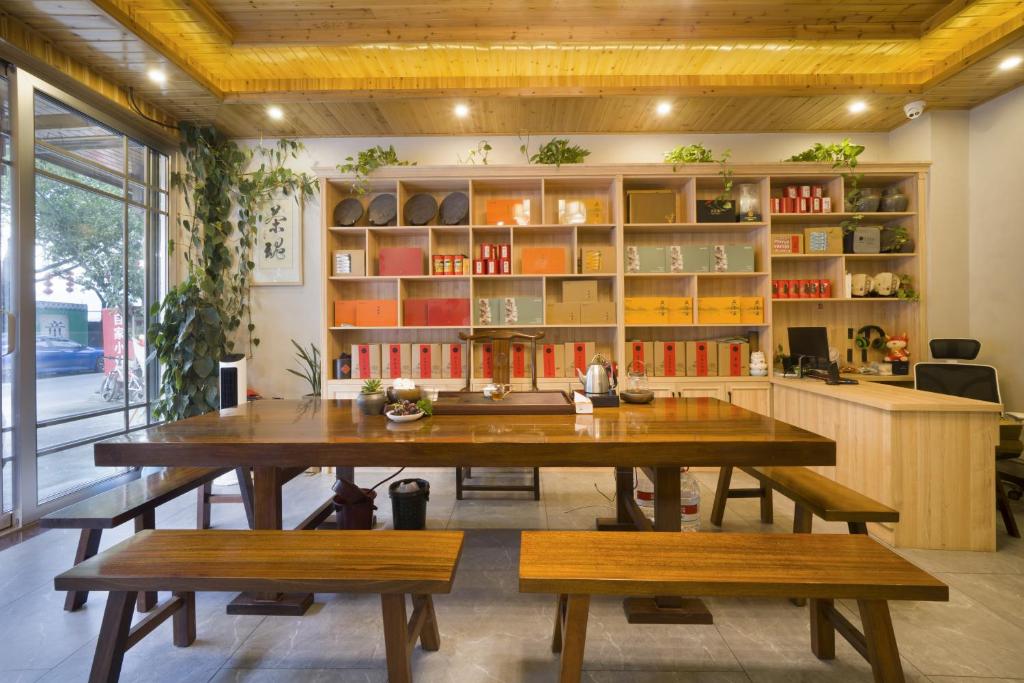 une salle à manger avec une grande table et des bancs en bois dans l'établissement Qianxun Tea House & Homestay, à Wuyishan