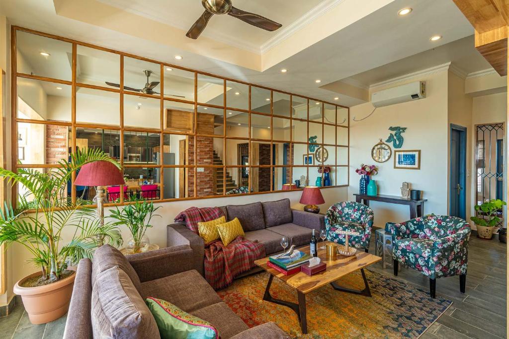 ダルムシャーラにあるStayVista at Creek Edge Home - Pet Friendly Villa with Mountain Views, Lawn, Near Water Streamのソファと椅子のあるリビングルーム