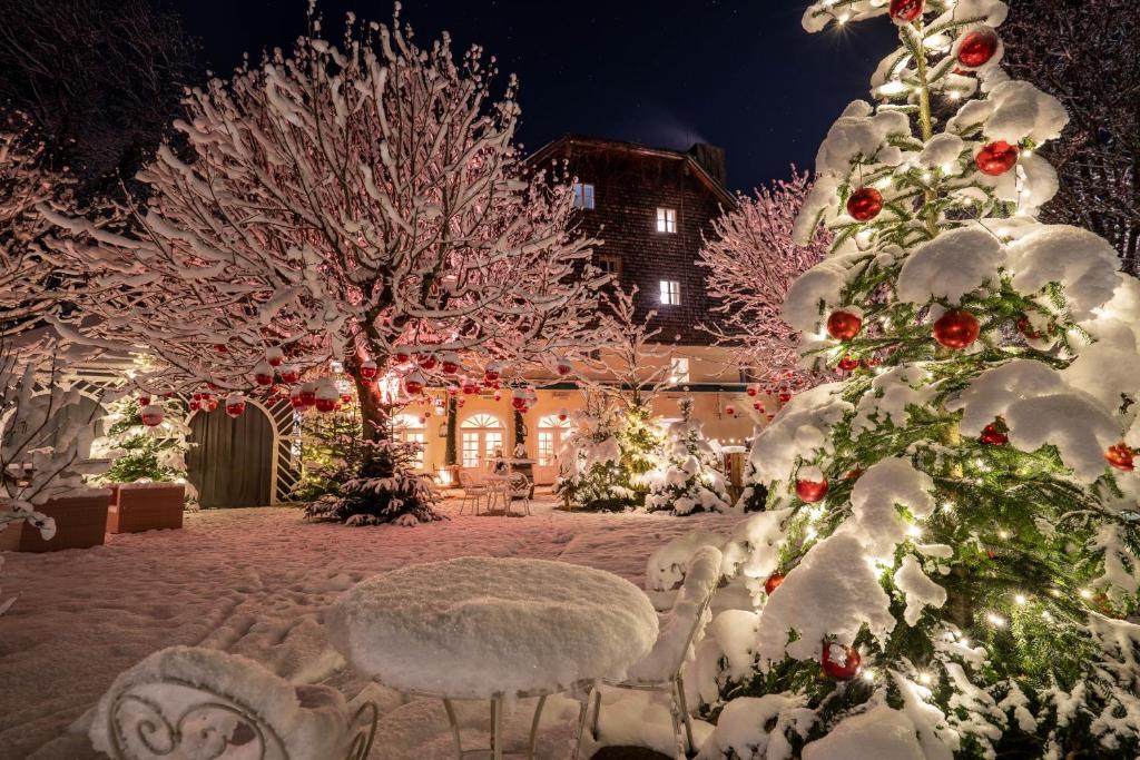 a christmas yard with snow covered trees and lights at Der Schlosswirt zu Anif - Biedermeierhotel und Restaurant in Anif