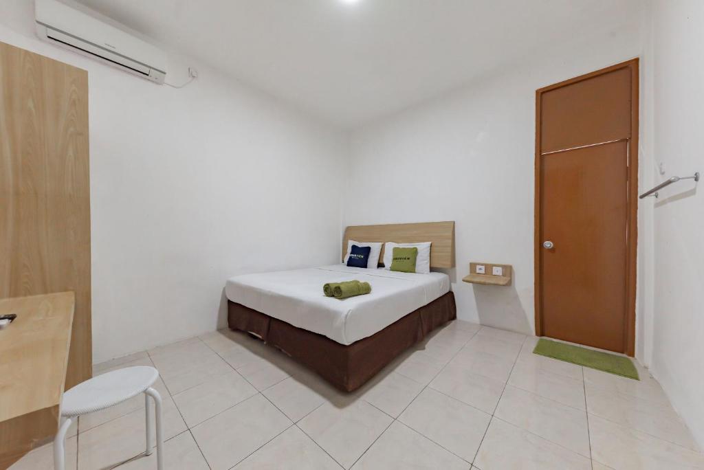 a bedroom with a bed in a white room at Urbanview Hotel Cozy Samarinda by RedDoorz in Samarinda