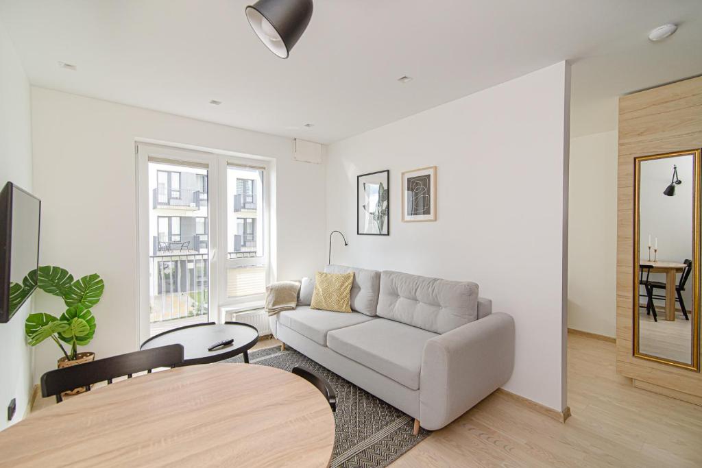 a white living room with a couch and a table at Modern Apartment Next to Ozas park by URBAN RENT in Vilnius