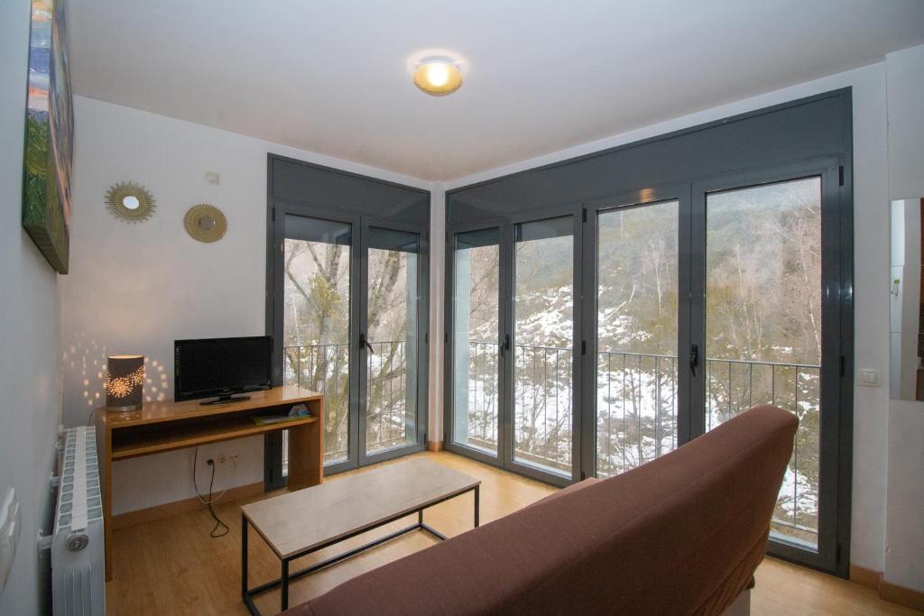 Una sala de estar con un sofá y algunas ventanas. en Apartamentos Canillo 3000, en Canillo