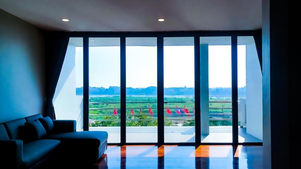 a living room with a couch and a large glass window at The Riva Vientiane Hotel in Vientiane