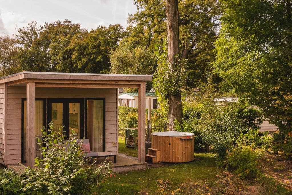 une petite cabine avec baignoire à côté d'un arbre dans l'établissement Vakantiepark Mölke, à Zuna