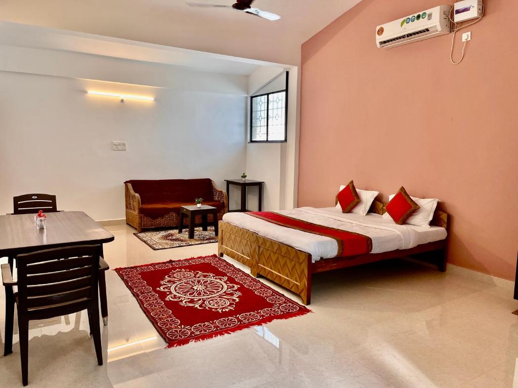 een slaapkamer met een bed, een tafel en een bureau bij St. Anthony guest house. in Anjuna