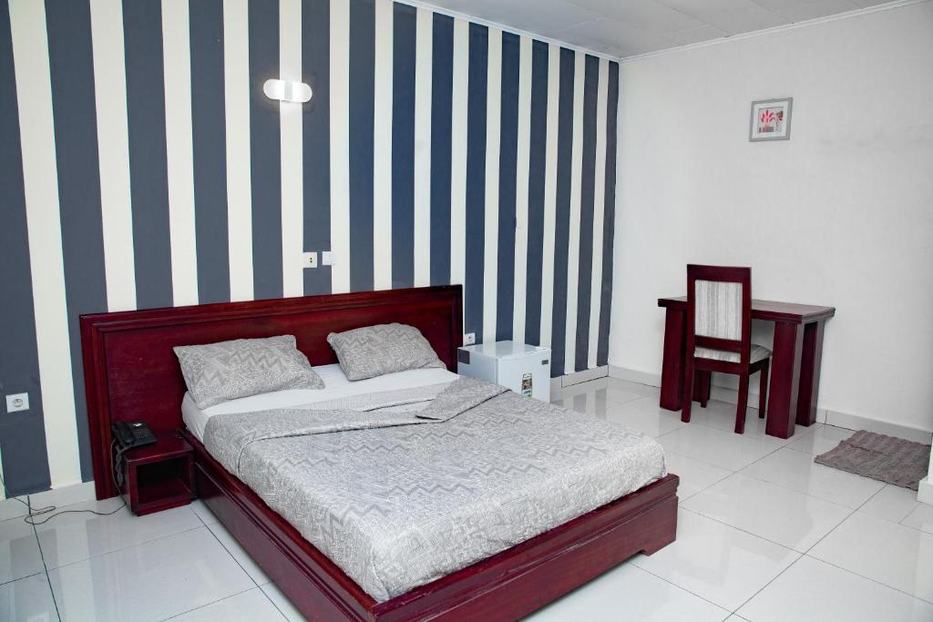 - une chambre avec un lit et un mur rayé dans l'établissement krEMLin, à Douala