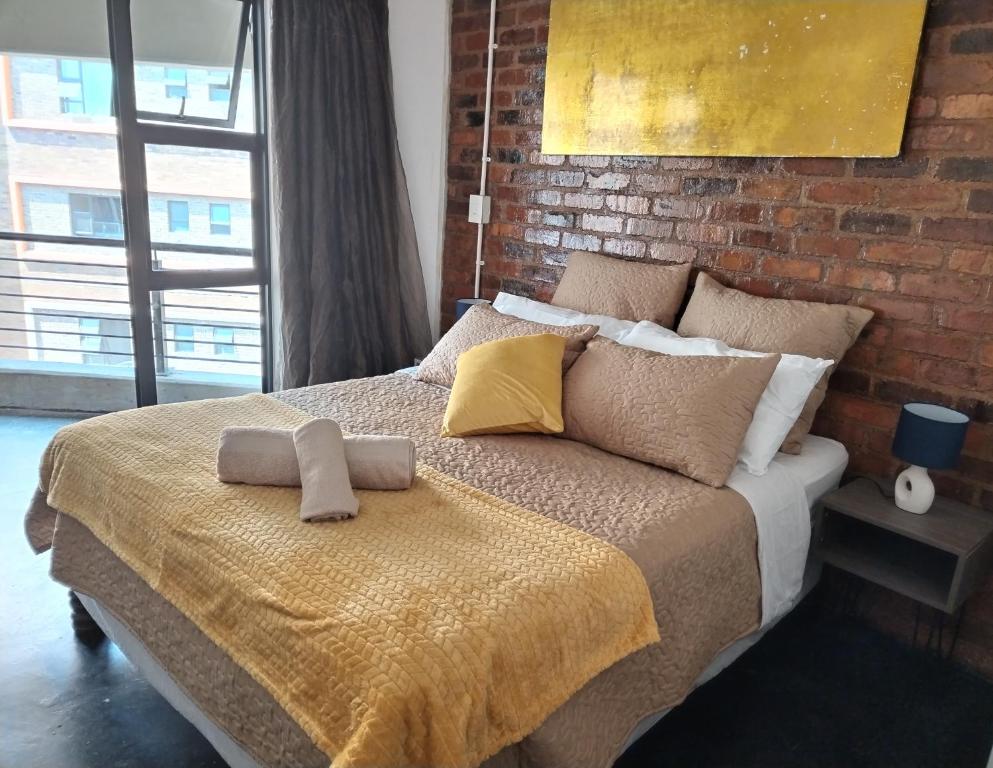 a bedroom with a bed with a brick wall at Maboneng Precinct Johannesburg - Craftsmenship Apartments in Johannesburg