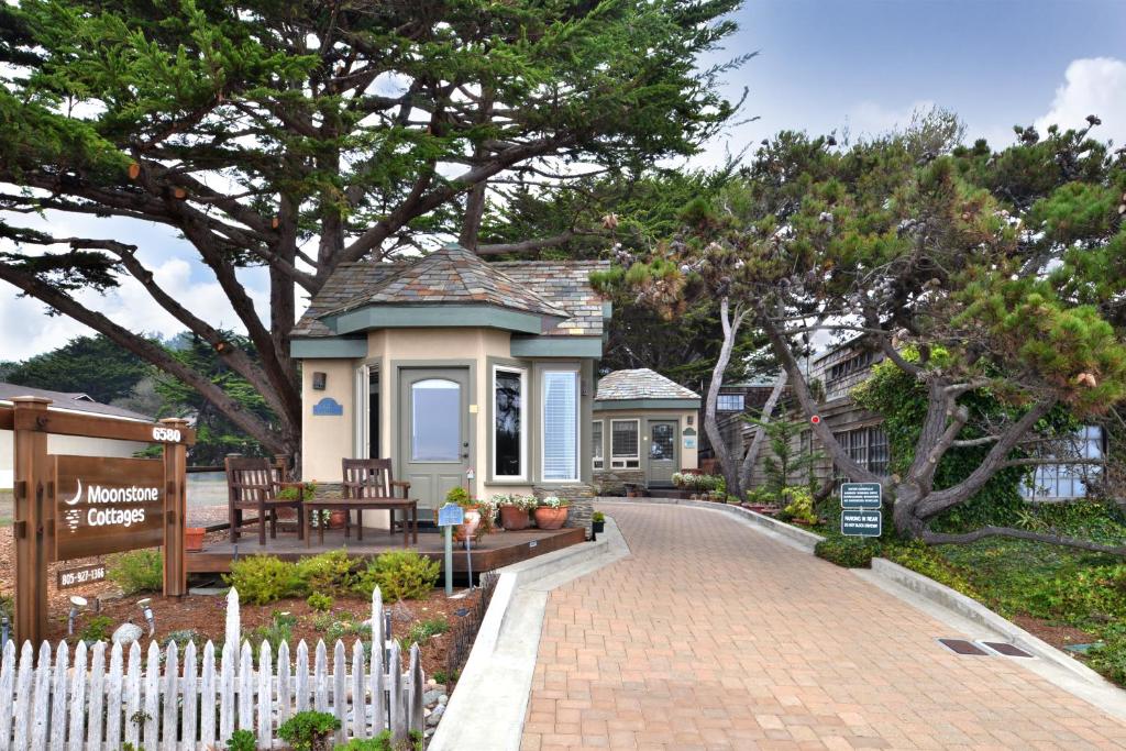 a small house with a white fence and a brick driveway at Moonstone Cottages in Cambria