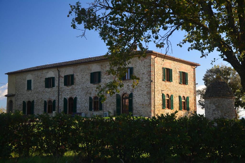 un vecchio edificio in pietra con un albero di fronte di Podere Campiano a Volterra