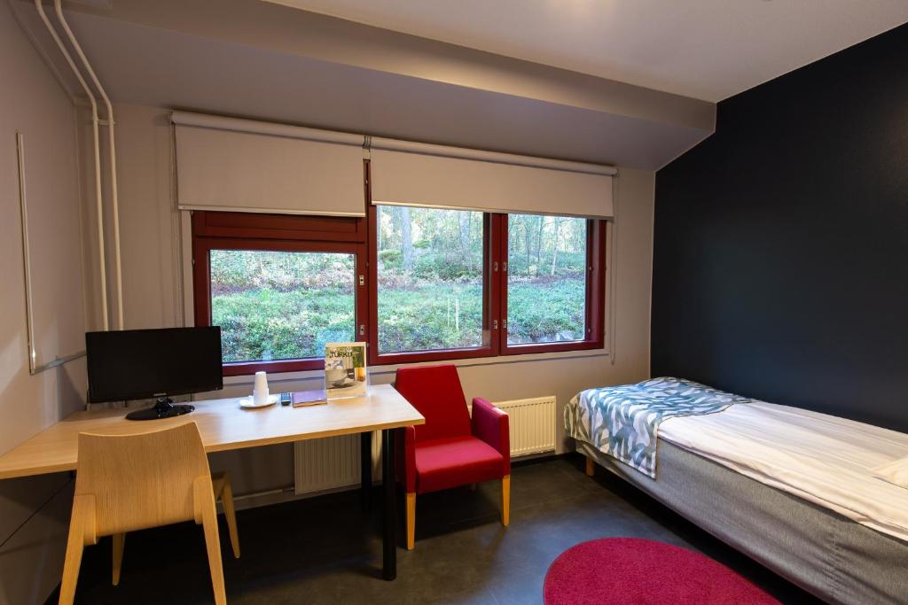 Hotel Linnasmäki في توركو: غرفة نوم مع مكتب وسرير ومكتب مع جهاز كمبيوتر