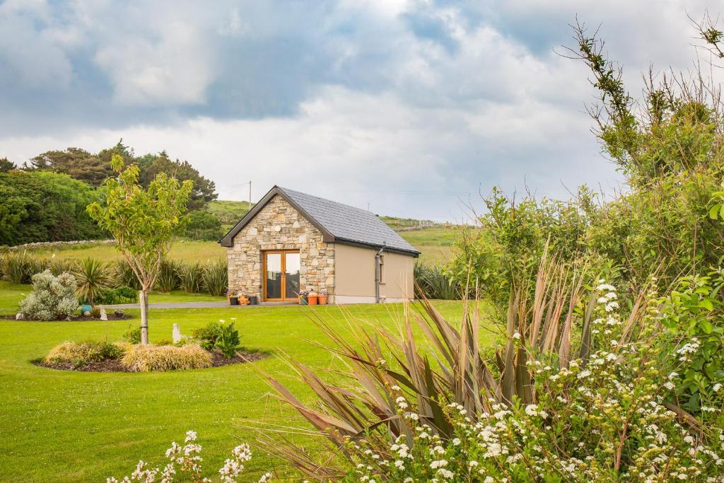 a stone cottage in the middle of a garden at ocean view cleggan in Cleggan