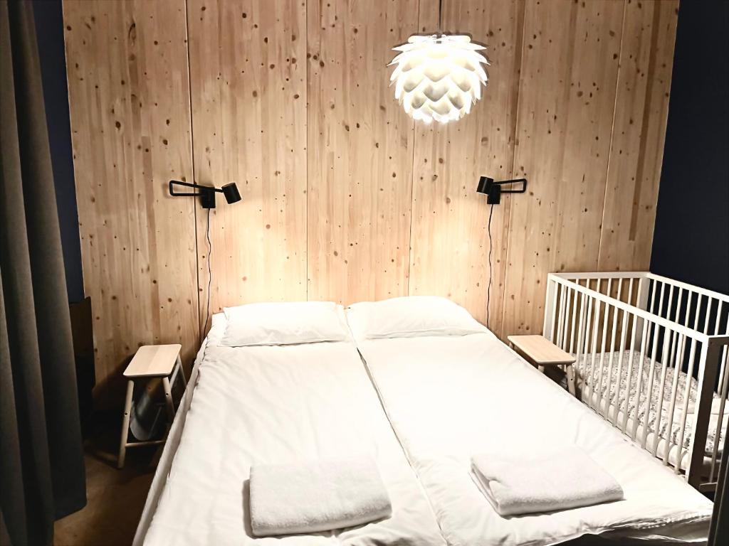 - une chambre avec un lit blanc et un mur en bois dans l'établissement Rudle, à Świerkocin