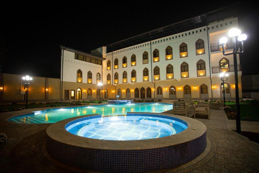 a large building with a swimming pool at night at Rayyan Hotel Samarkand in Samarkand