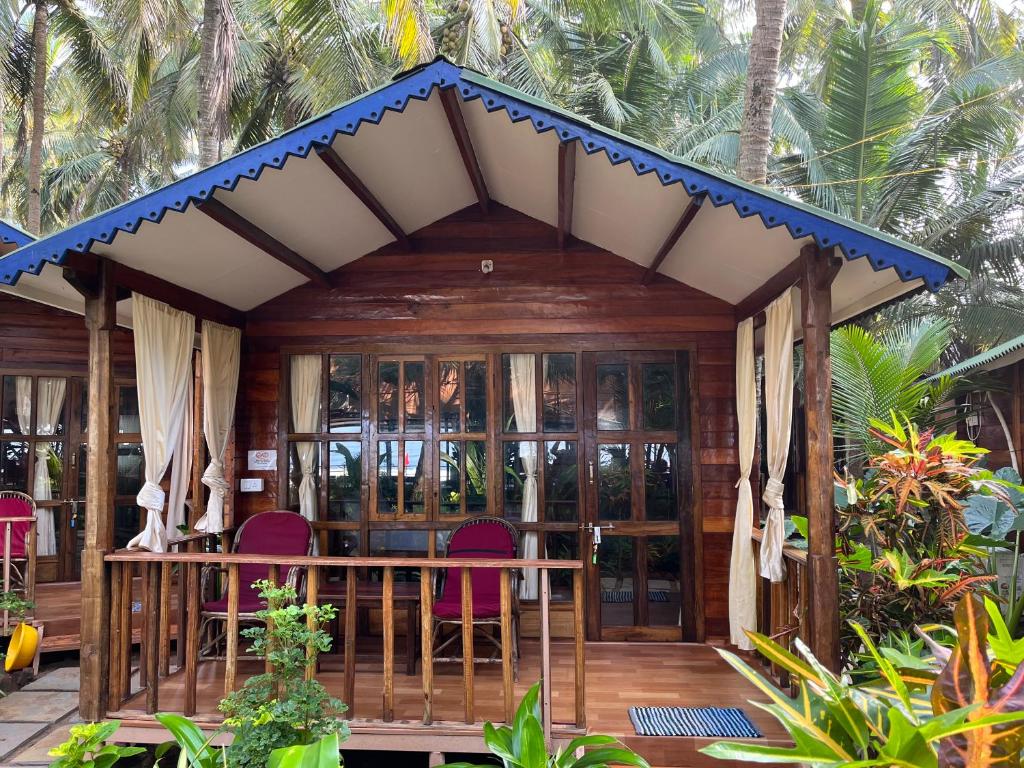 a cabin with a table and chairs on a porch at Jardim a Mar in Agonda