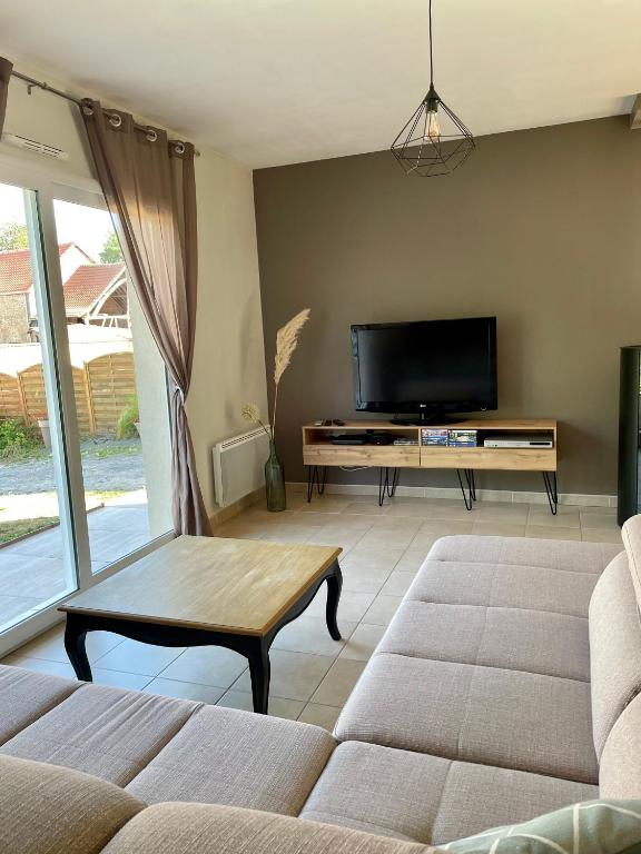 a living room with a couch and a flat screen tv at L&#39;écureuil de la Baie - maison en Baie de Somme in Mons-Boubert
