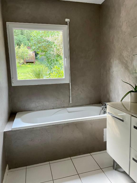 a bathroom with a bath tub and a window at L&#39;écureuil de la Baie - maison en Baie de Somme in Mons-Boubert