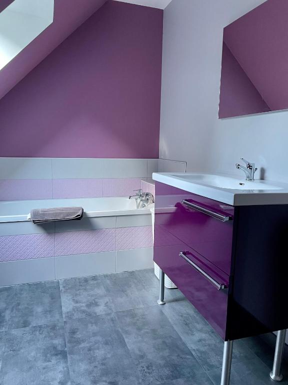 a purple bathroom with a sink and a bath tub at L&#39;écureuil de la Baie - maison en Baie de Somme in Mons-Boubert