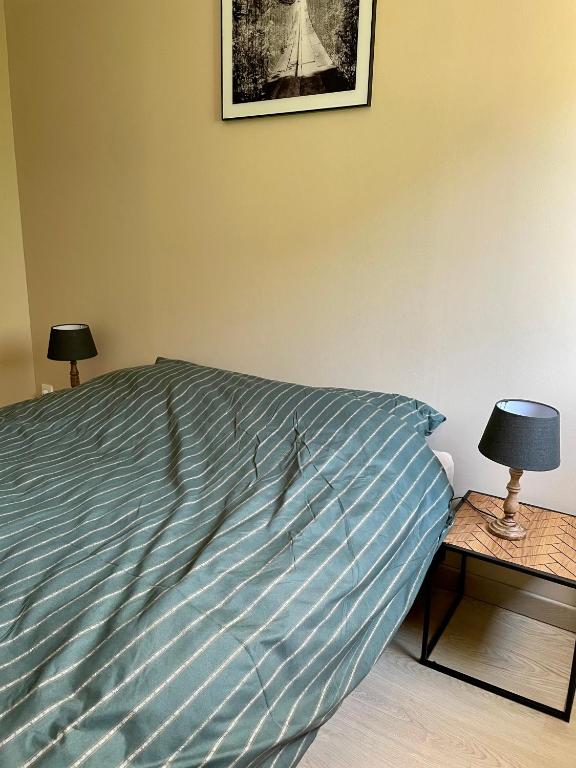 a bed with a blue comforter and two lamps at L&#39;écureuil de la Baie - maison en Baie de Somme in Mons-Boubert