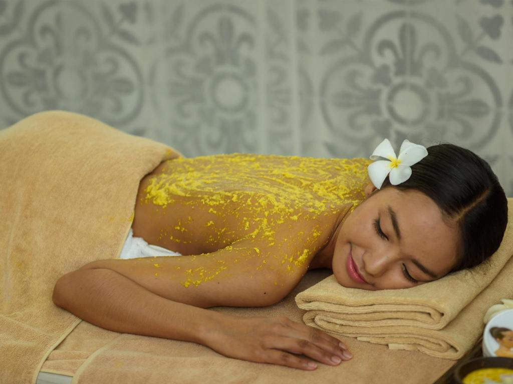 a woman in a yellow dress sleeping on a towel at Lynnaya Urban River Resort in Siem Reap