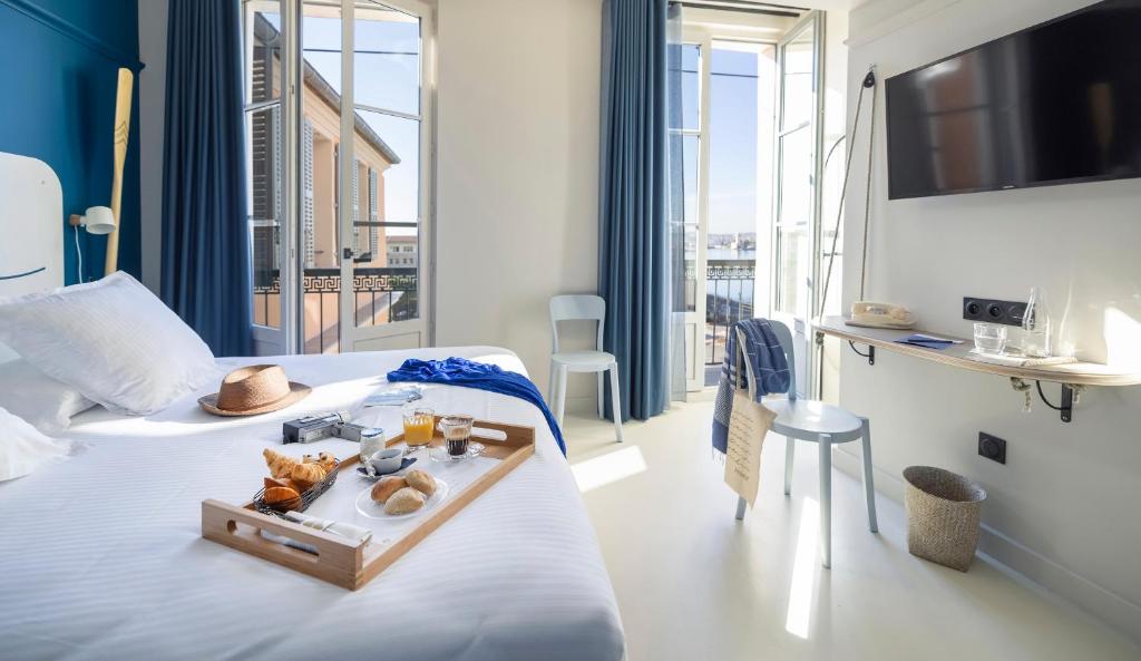 a hotel room with a bed with a tray of food on it at L'Eautel Toulon Centre Port in Toulon