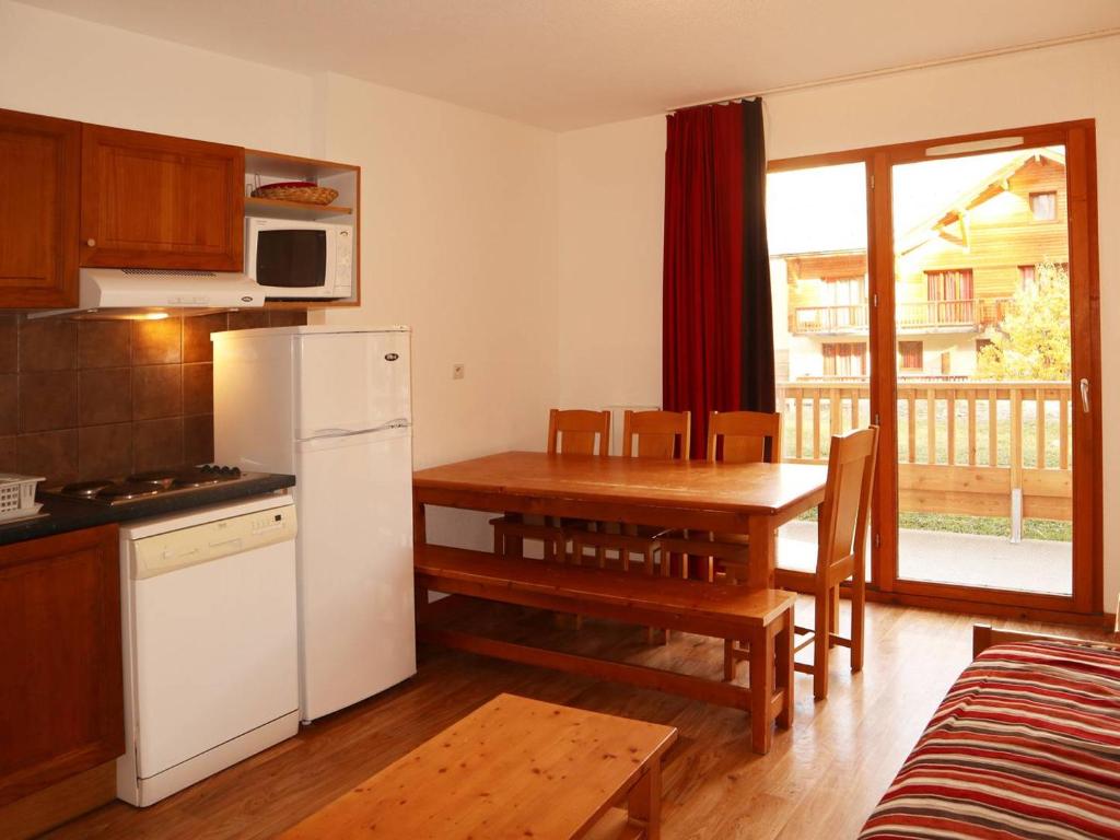 Il comprend une cuisine et une salle à manger avec une table et un réfrigérateur. dans l'établissement Grand appartement pour 8 avec piscine intérieure chauffée, jacuzzi et grande terrasse exposée sud - FR-1-322-378, aux Orres