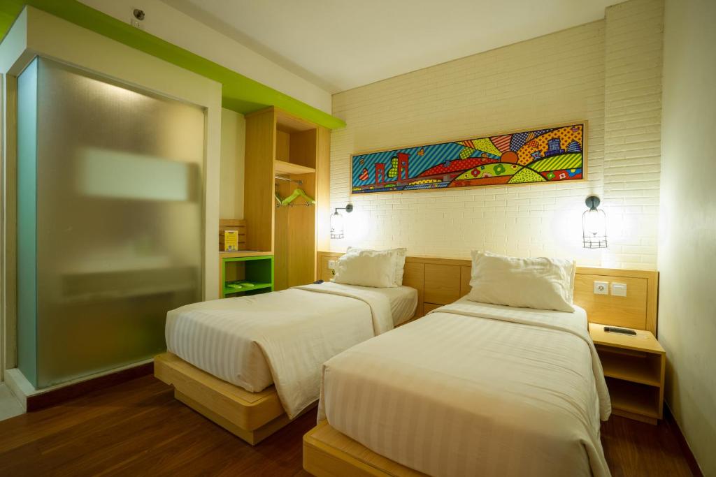 una habitación de hotel con 2 camas y un cuadro en la pared en MaxOneHotels.com at Vivo Palembang, en Palembang