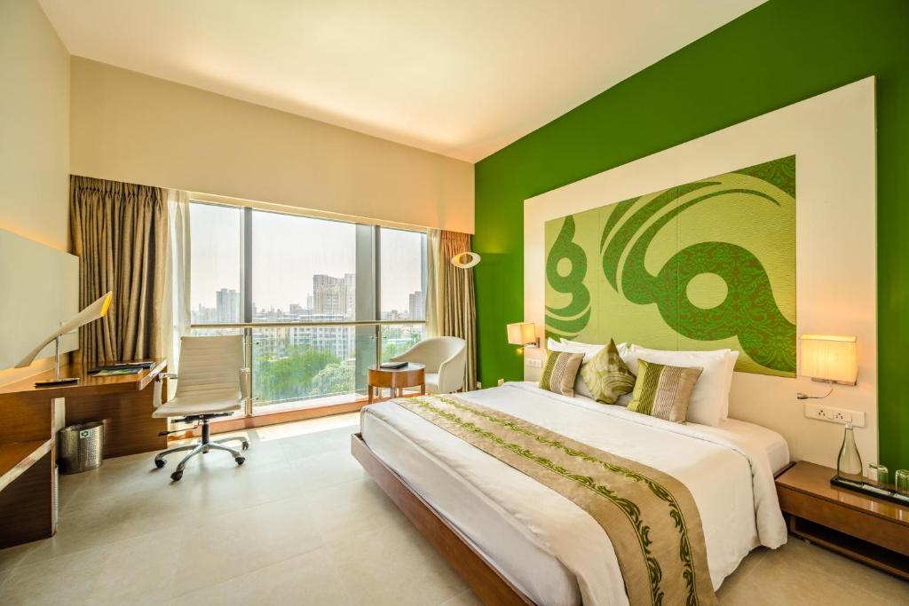 ムンバイにあるThe Fern Residency Mumbaiの緑の壁のベッドルーム1室(大型ベッド1台付)