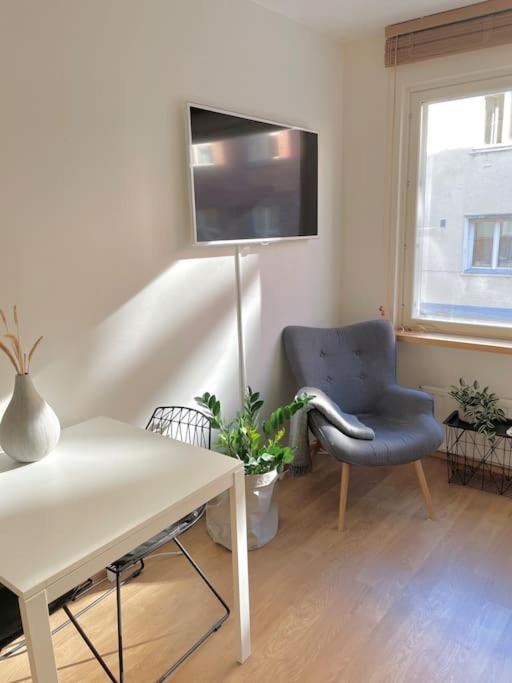a living room with a table and a chair and a television at Lovely studio in the famous Design District area. in Helsinki