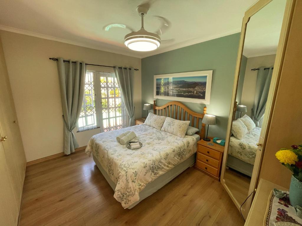 a bedroom with a bed and a large mirror at Lemon Tree Cottage in Edgemead