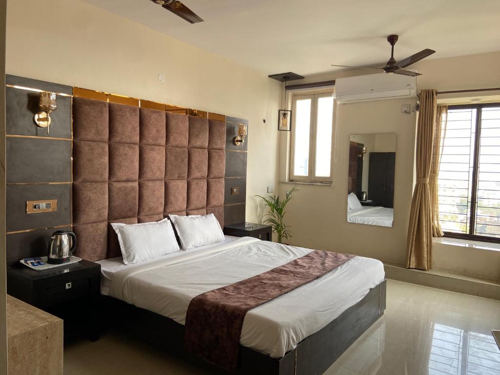 a bedroom with a large bed and a mirror at The Aster Penthouse in Kolkata