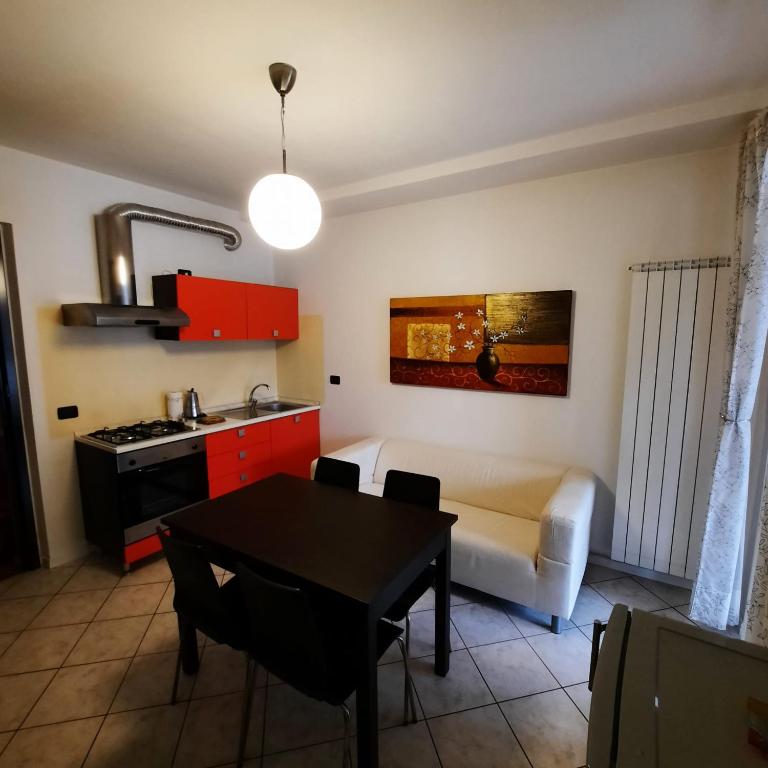 a kitchen and living room with a table and a couch at Appartamento Pizzo di Parlasco - Your Mountain Holiday in Taceno