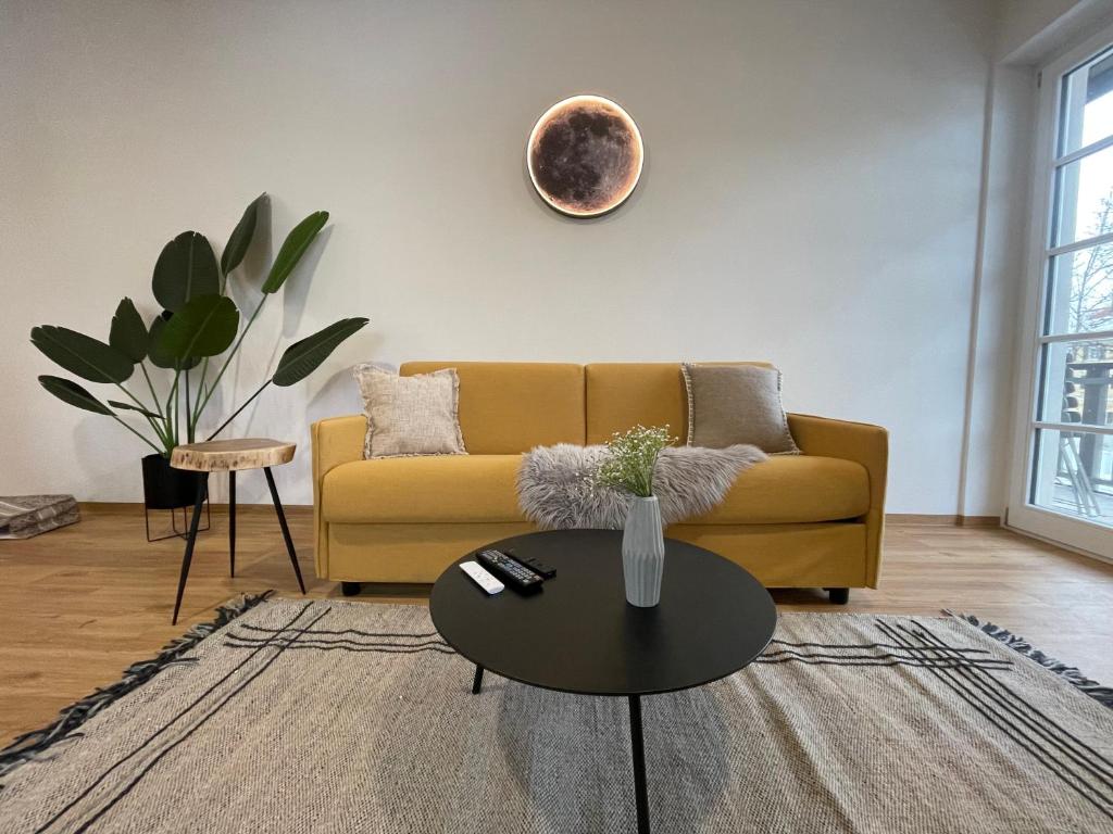 a living room with a yellow couch and a table at Gmund Seeliebe Premiumsuite in Gmund am Tegernsee