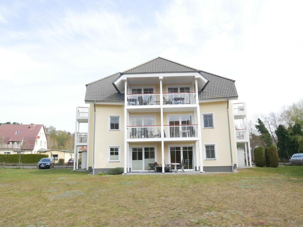 uma grande casa branca com um quintal em frente em Bernsteinhaus, 850m zum Strand, mit Balkon, WLAN em Kolpinsee