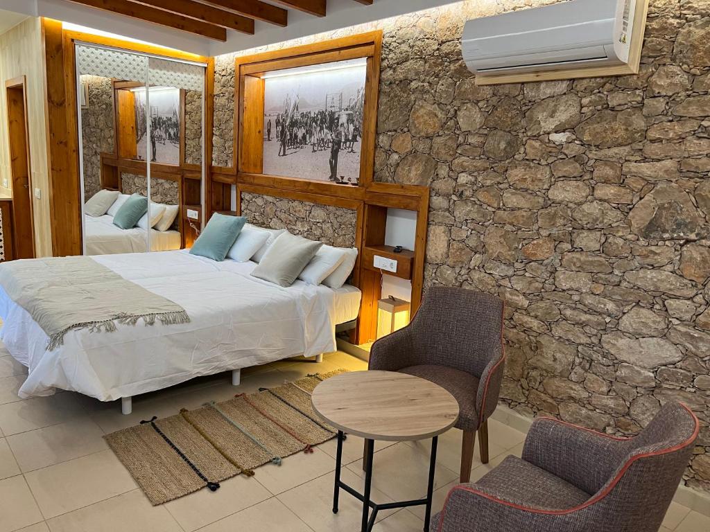 Hotel Rural Rosario Martin في بويرتو ديل روزاريو: غرفة نوم بسرير وطاولة وكراسي