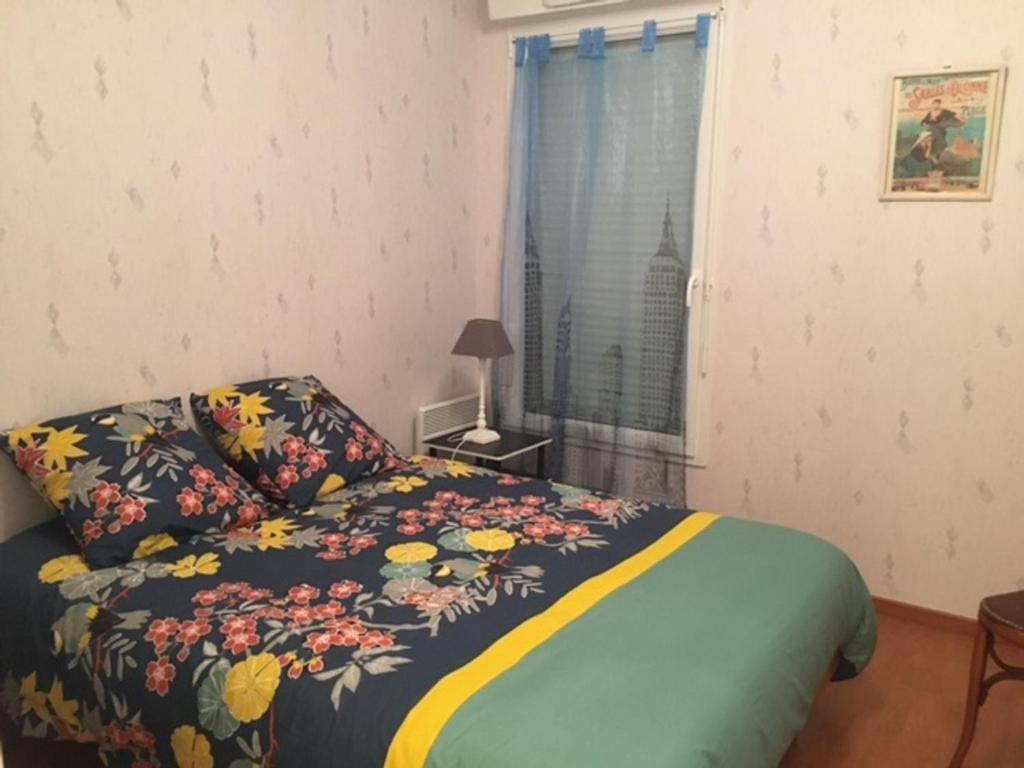 - une chambre avec un lit doté d'un couvre-lit floral et d'une fenêtre dans l'établissement Appartement Tout Confort avec Parking, Proche Plage et Commerces - FR-1-197-509, à Les Sables-dʼOlonne