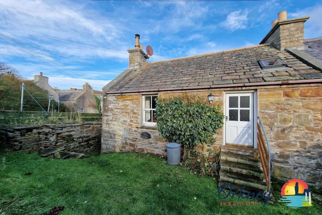 Ce cottage en pierre dispose d'une porte blanche et d'une fenêtre. dans l'établissement Khyber Pass Cottage, Stromness - OR00332F, à Stromness