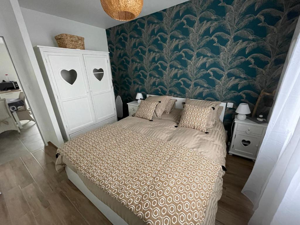 een slaapkamer met een bed met een blauwe muur bij Repos paisible in Talmont