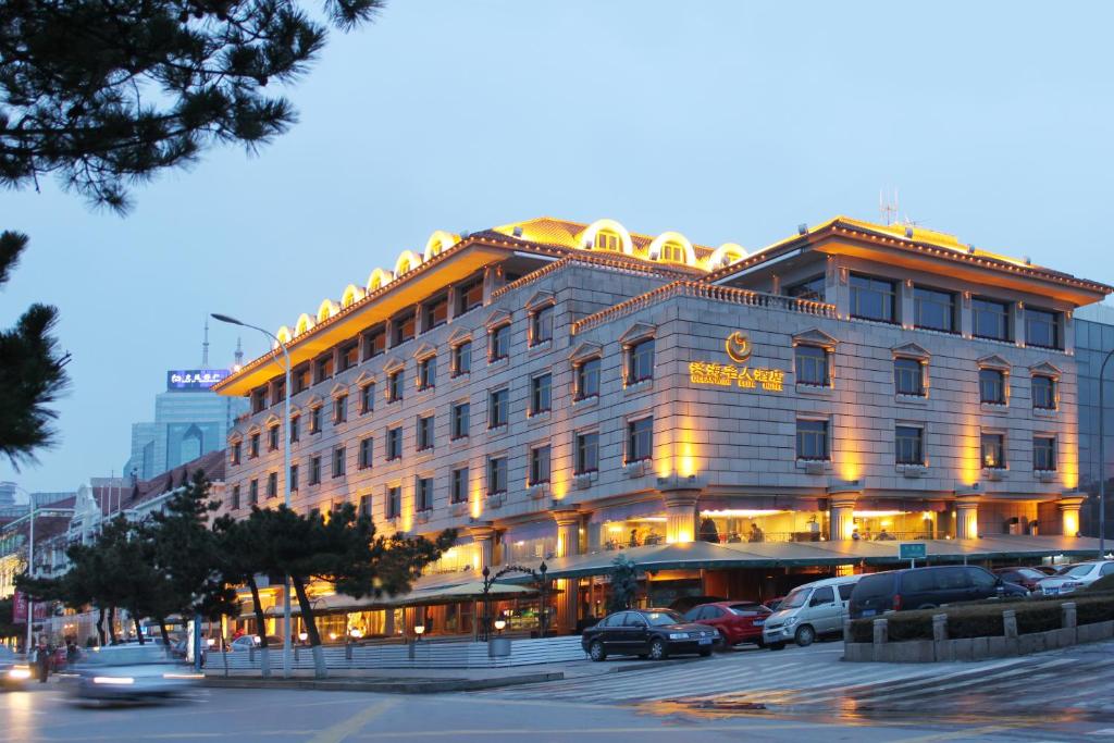 un grand bâtiment avec des voitures garées devant lui dans l'établissement Qingdao Oceanwide Elite Hotel, à Qingdao