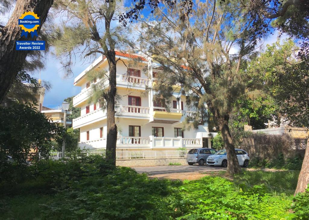 a white house with cars parked in front of it at A&B Rhodes city apartments in Rhodes Town