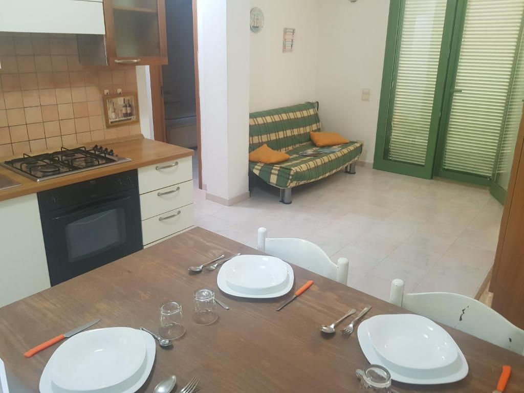 a kitchen with a table with white plates on it at Appartamenti Oleandri Baia Verde in Gallipoli