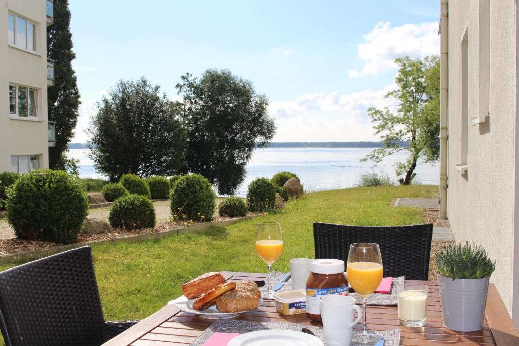una mesa con vasos de zumo de naranja y pan. en FerienWohnung SeeUfer am Plöner See, en Ascheberg