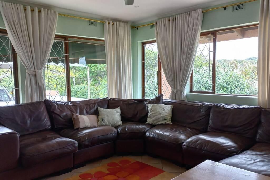 a brown leather couch in a living room with windows at Guest house Winklespruit in Kingsborough