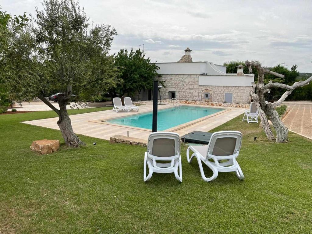 duas cadeiras de jardim e uma mesa ao lado de uma piscina em Casale dolina verde em Ostuni
