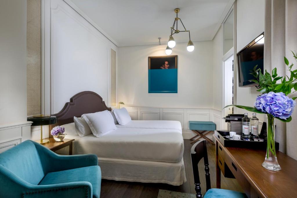 a bedroom with a bed and two blue chairs at Boutique Hotel H10 Villa de la Reina in Madrid