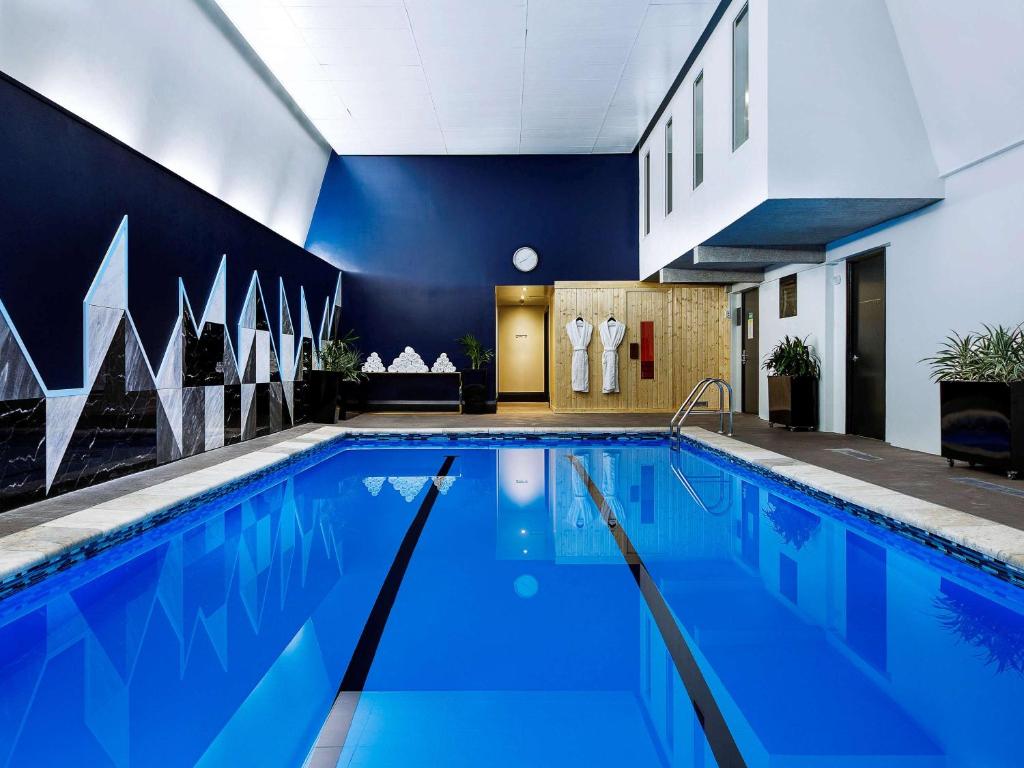 a swimming pool with blue water in a building at Mövenpick Hotel Wellington in Wellington