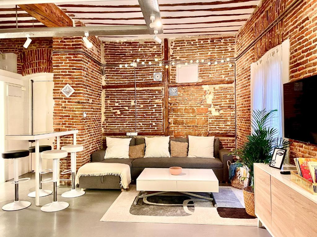 uma sala de estar com um sofá e uma parede de tijolos em calle Amparo100 Red brick loft for 8 Madrid Lavapies em Madri