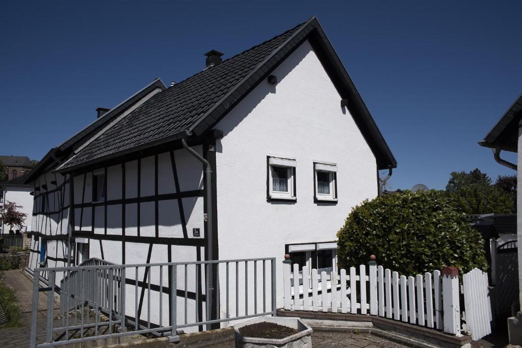 een wit huis met een zwart dak en een wit hek bij Rosige Zeiten, Ferien im Fachwerkhaus in Kommern