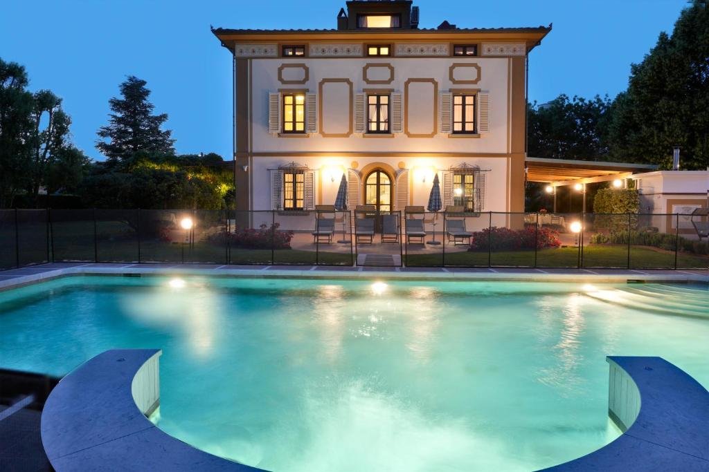 uma grande piscina em frente a uma casa à noite em Villa Colombai em Orentano