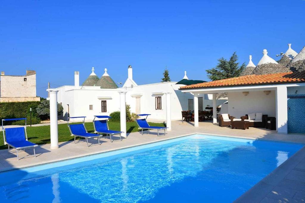 una piscina con sedie blu e una casa di Villa Giovanna Trullo a Ostuni